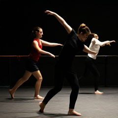Modern dance rehearsal captured in motion with dramatic lighting.
